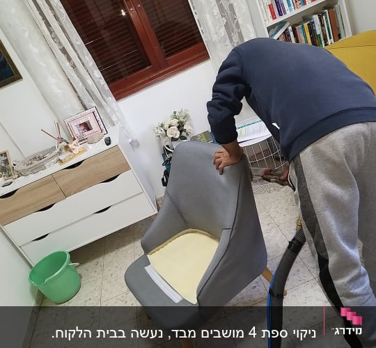 אדם מנקה כורסה עם שואב אבק